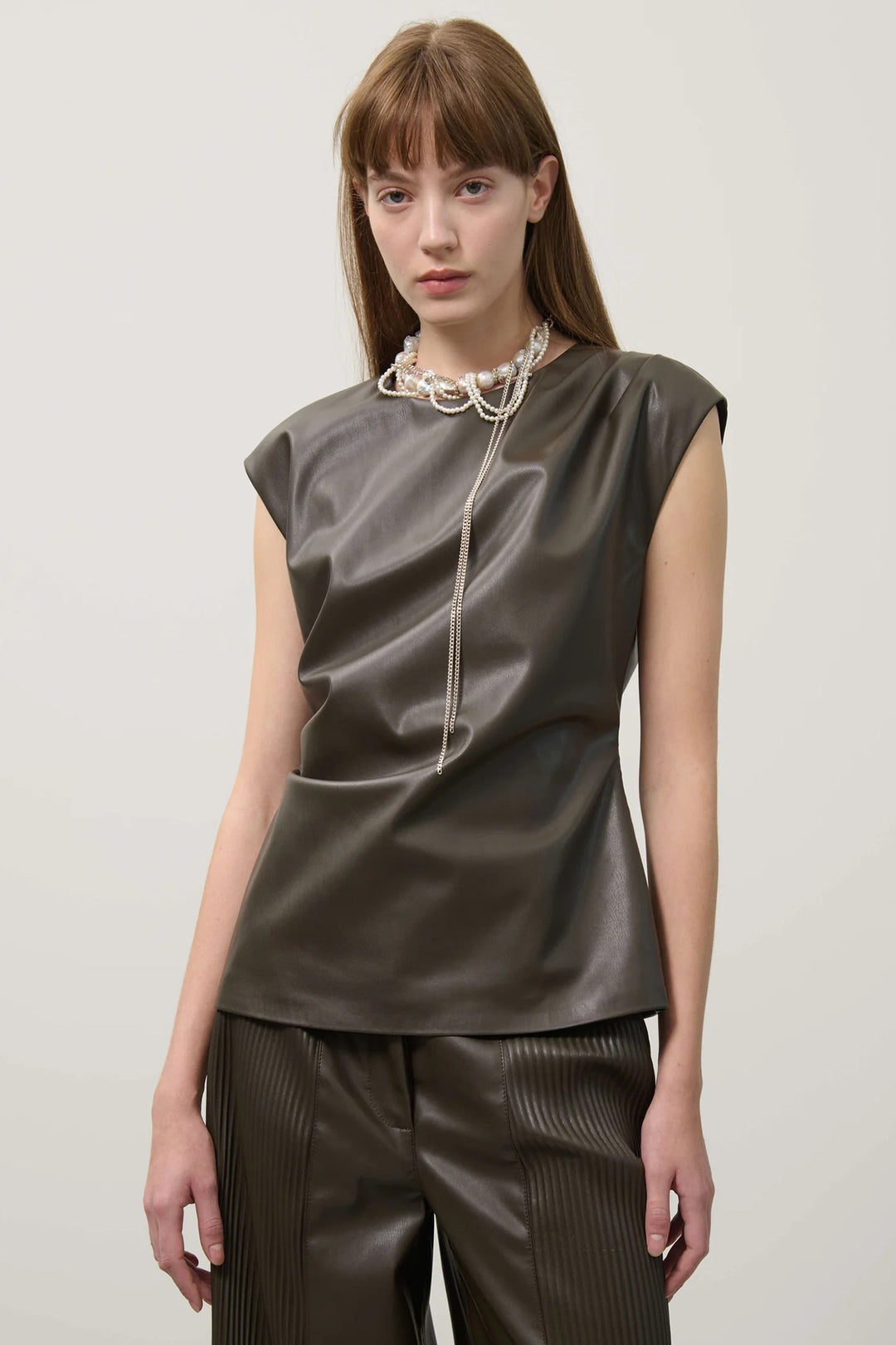 Woman wearing a sleeveless khaki top and matching pants against a plain background