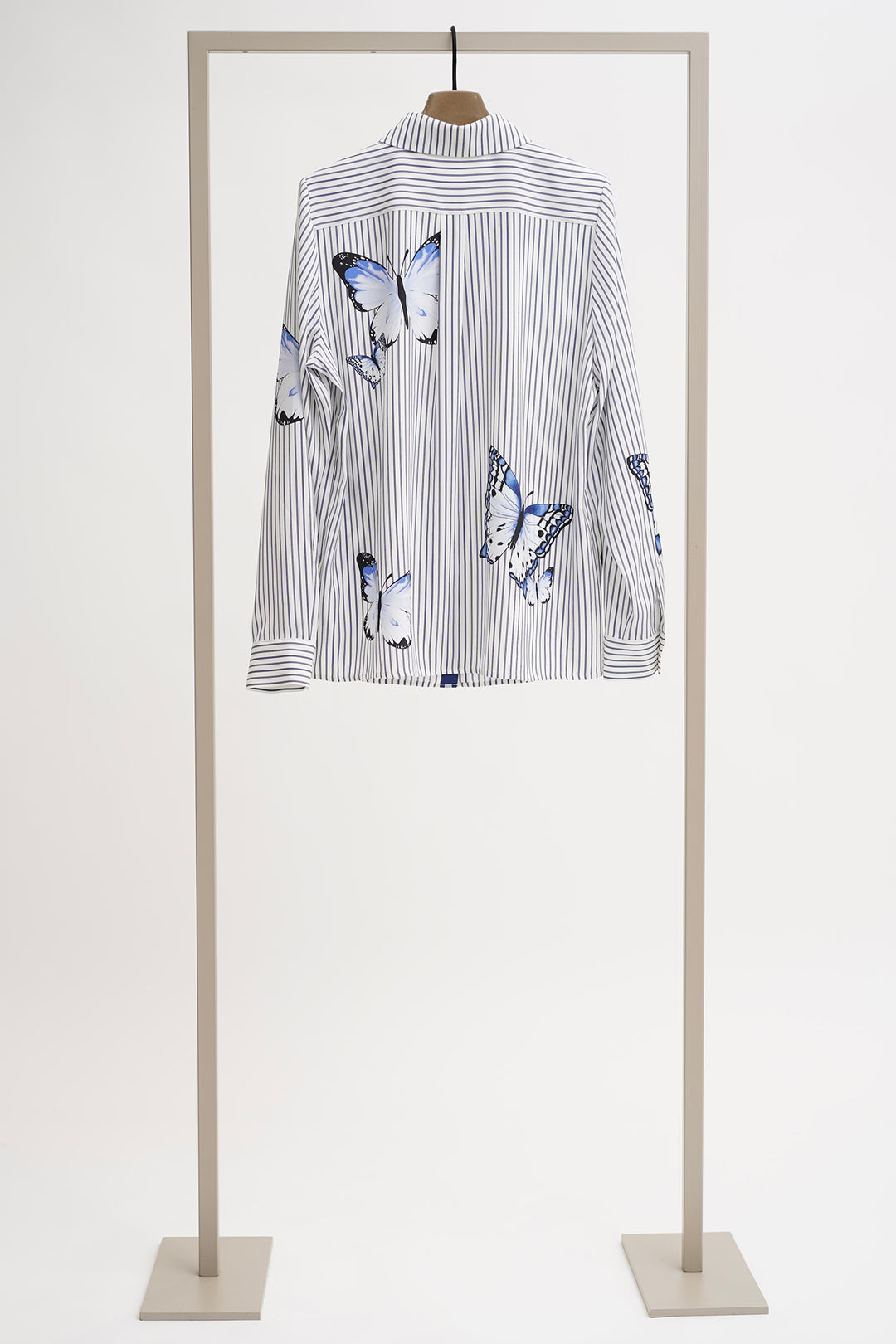 Striped shirt with butterfly designs on a mannequin against a white background