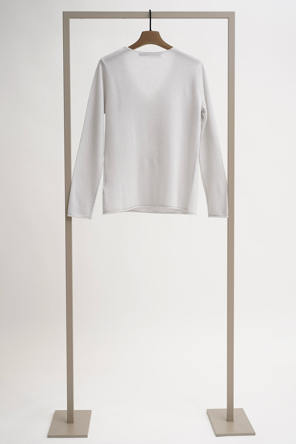 White long-sleeve shirt on a wooden hanger against a light gray background