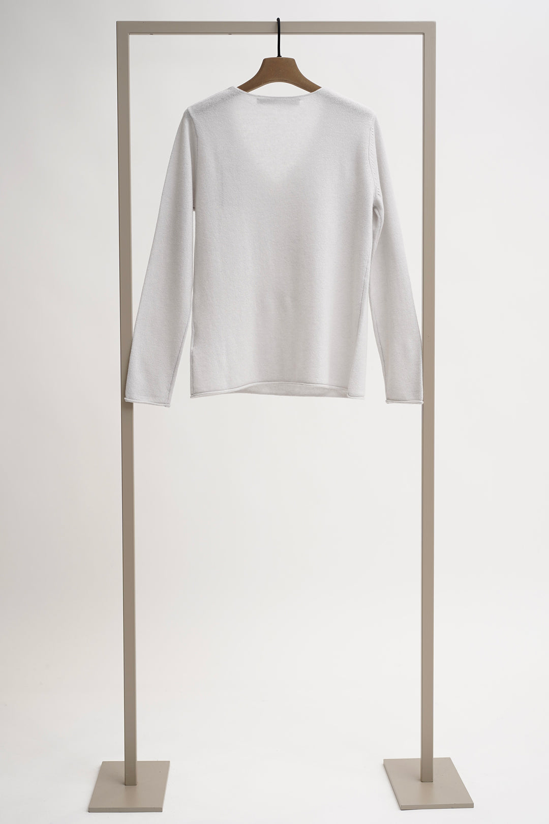 White long-sleeve shirt on a wooden hanger against a light gray background