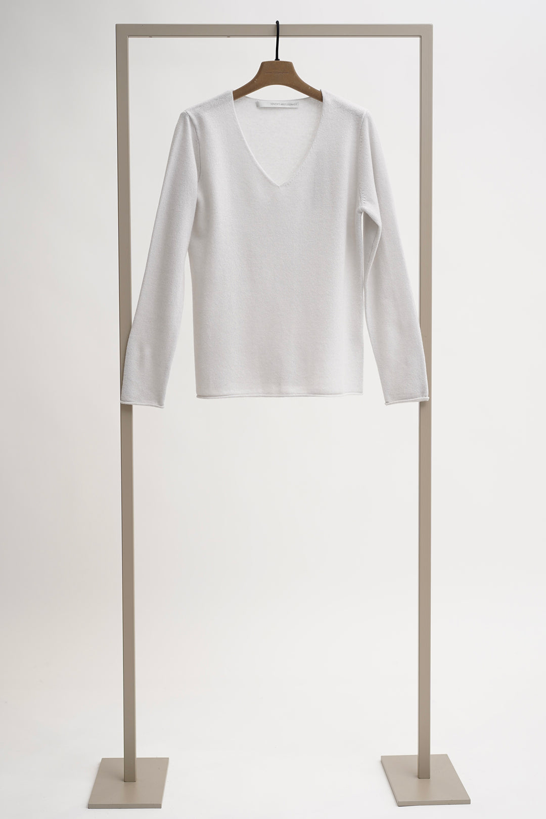 White long-sleeve shirt on a wooden hanger against a white background