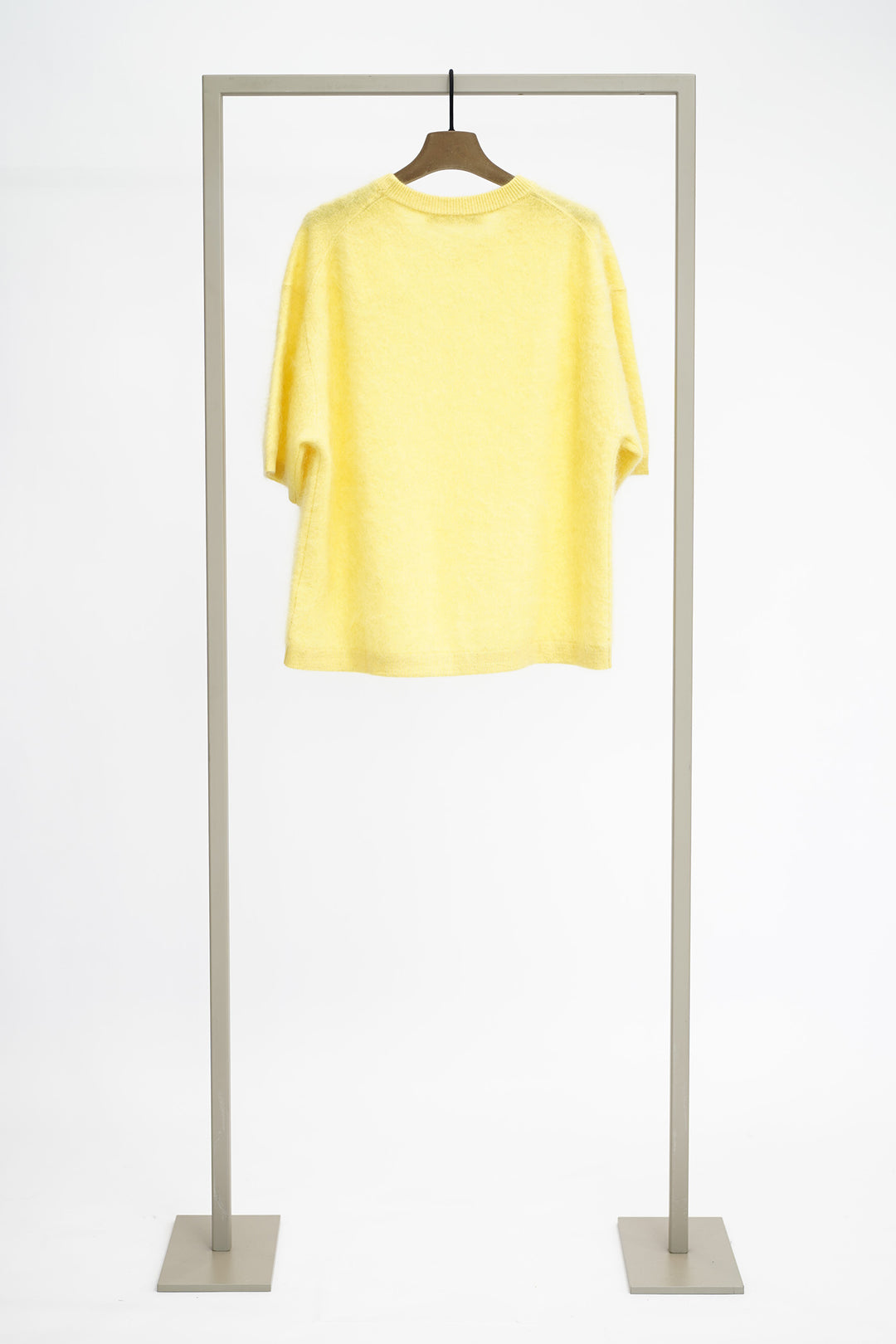 Yellow jumper from back on a hanger against a white background