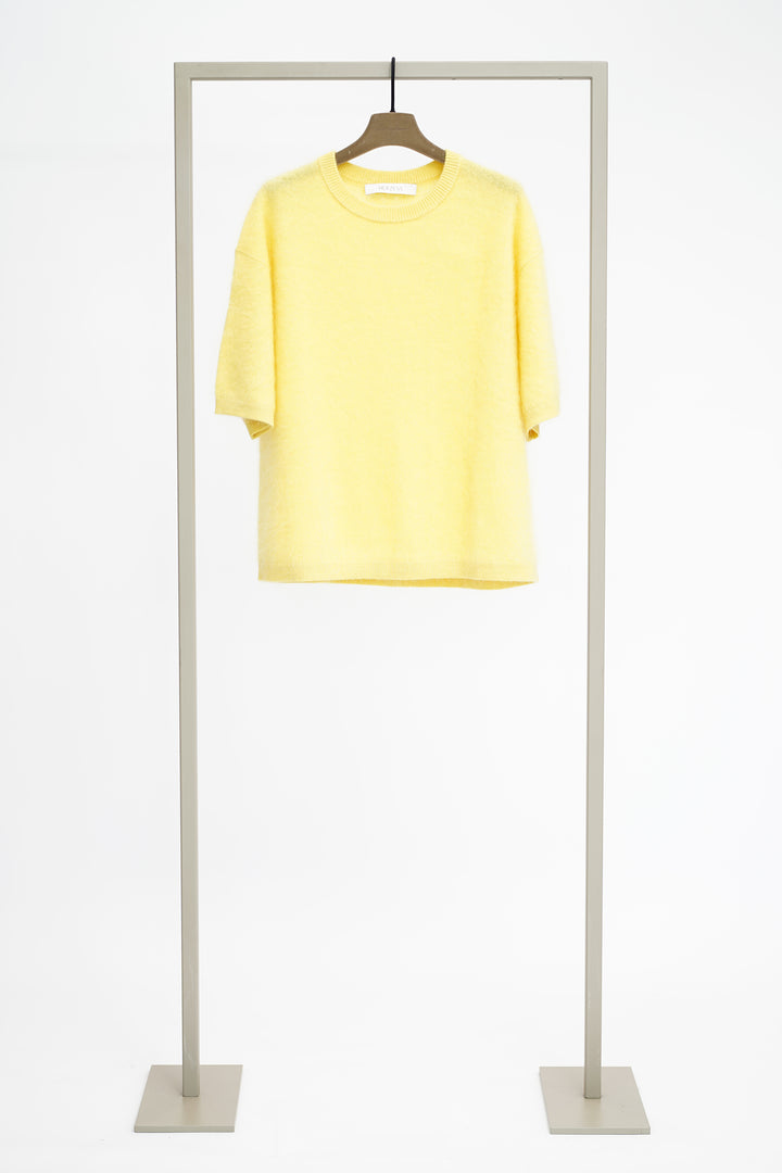 Yellow jumper on a hanger attached to a metal stand against a white background