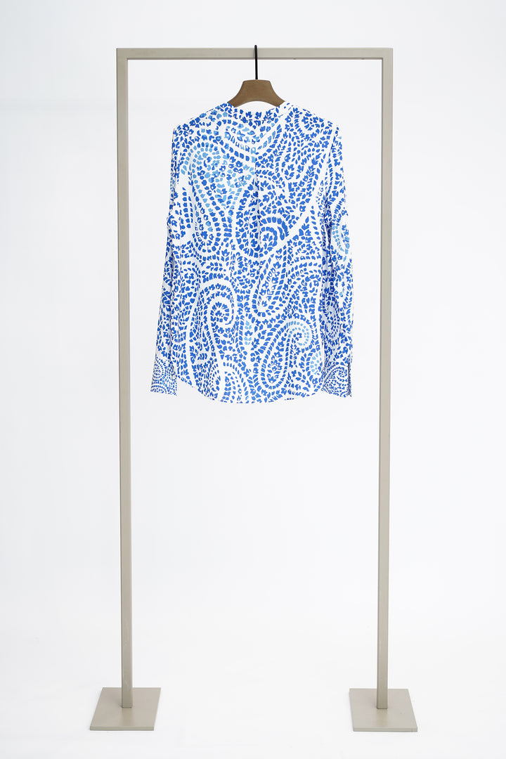 Blue and white patterned long sleeved blouse on a hanger against a white background