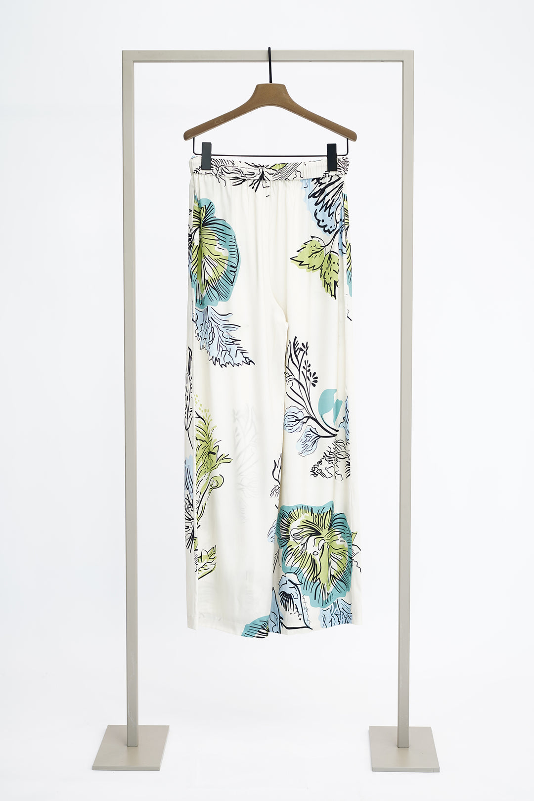 Large print floral trousers on a hanger against a white background