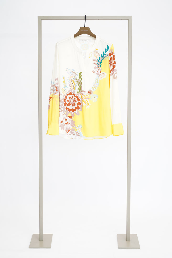 Floral print and yellow blouse with long sleeves on hanger against a white background