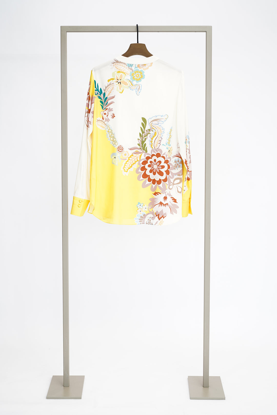 Floral print and yellow blouse with long sleeves from back on hanger against a white background