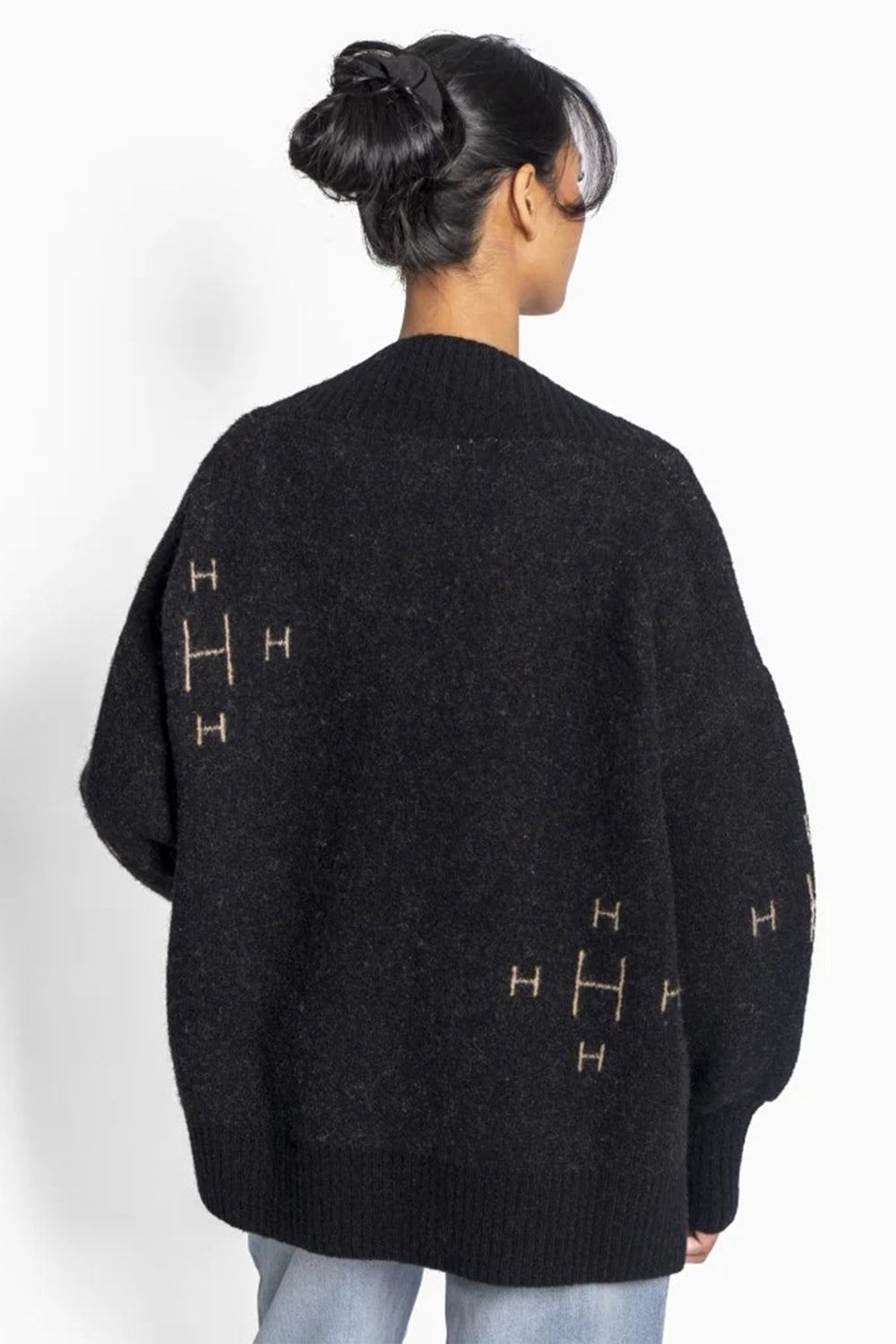 Person wearing a black sweater with gold symbols on a white background
