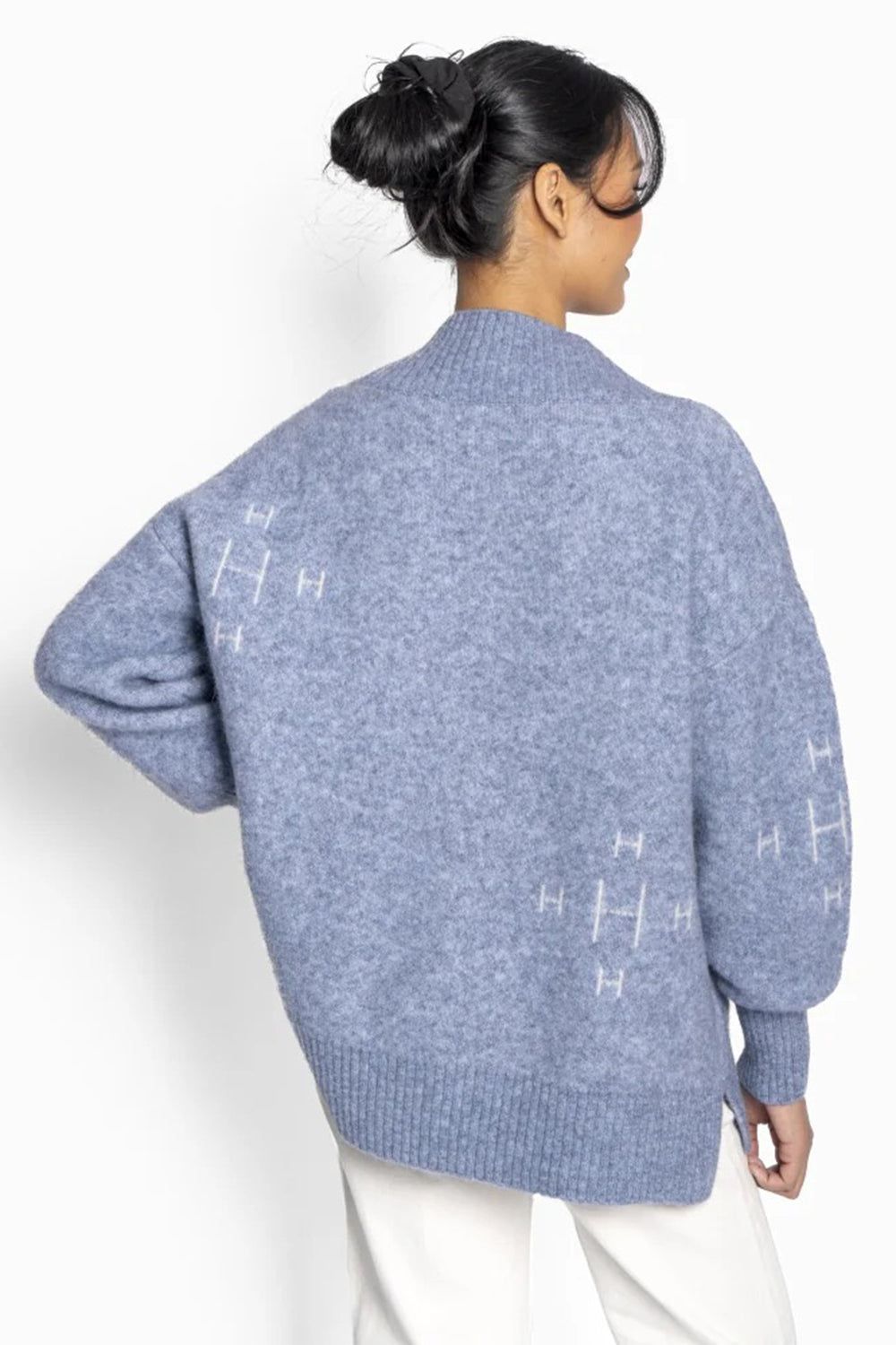 Person wearing a blue sweater with geometric patterns on a white background