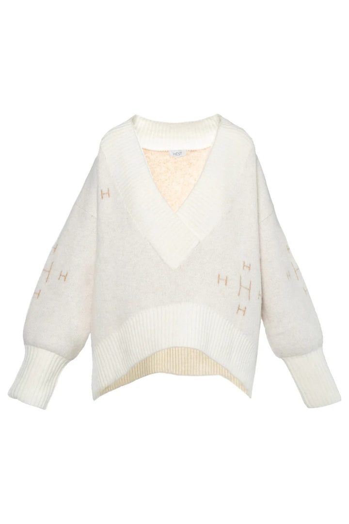 White sweater with embroidered details on a white background