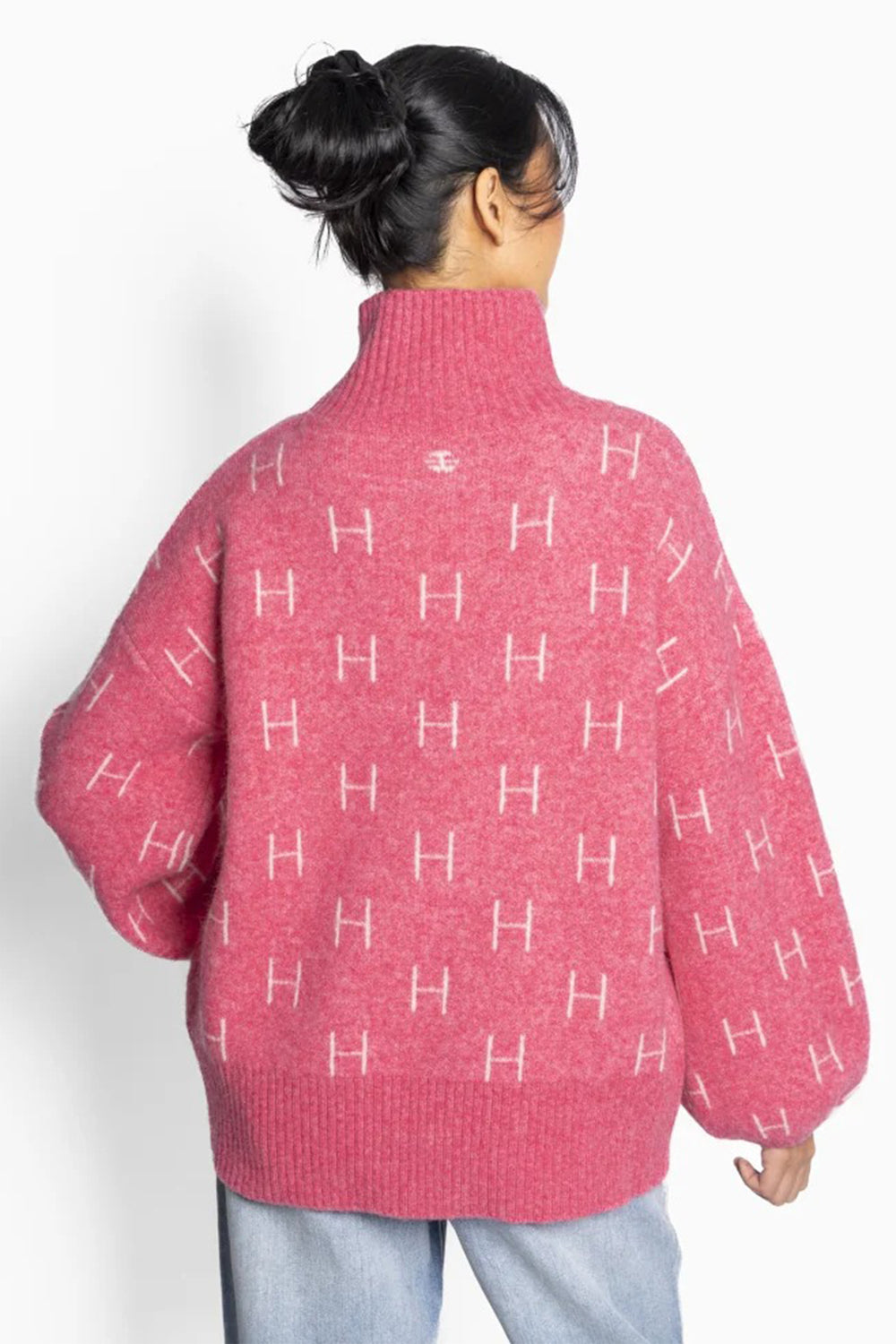 Person wearing a pink sweater with a pattern of 'H' on a white background