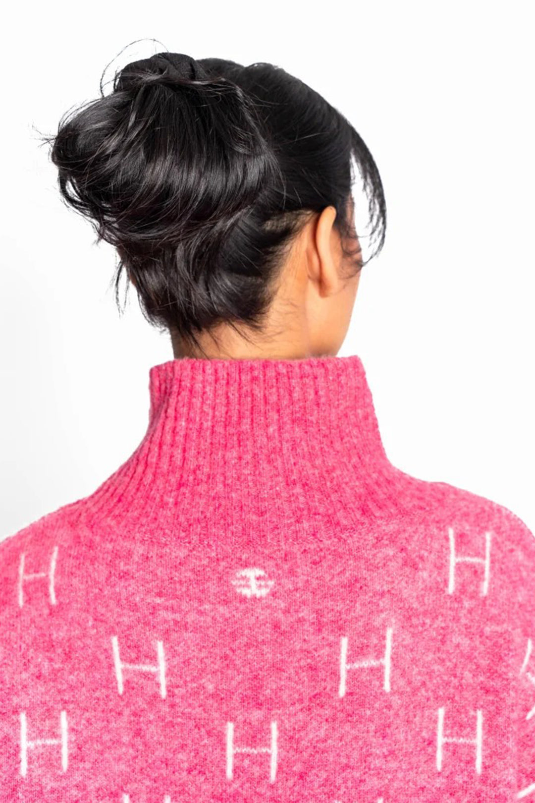 Person wearing a pink turtleneck sweater with white lettering on a white background