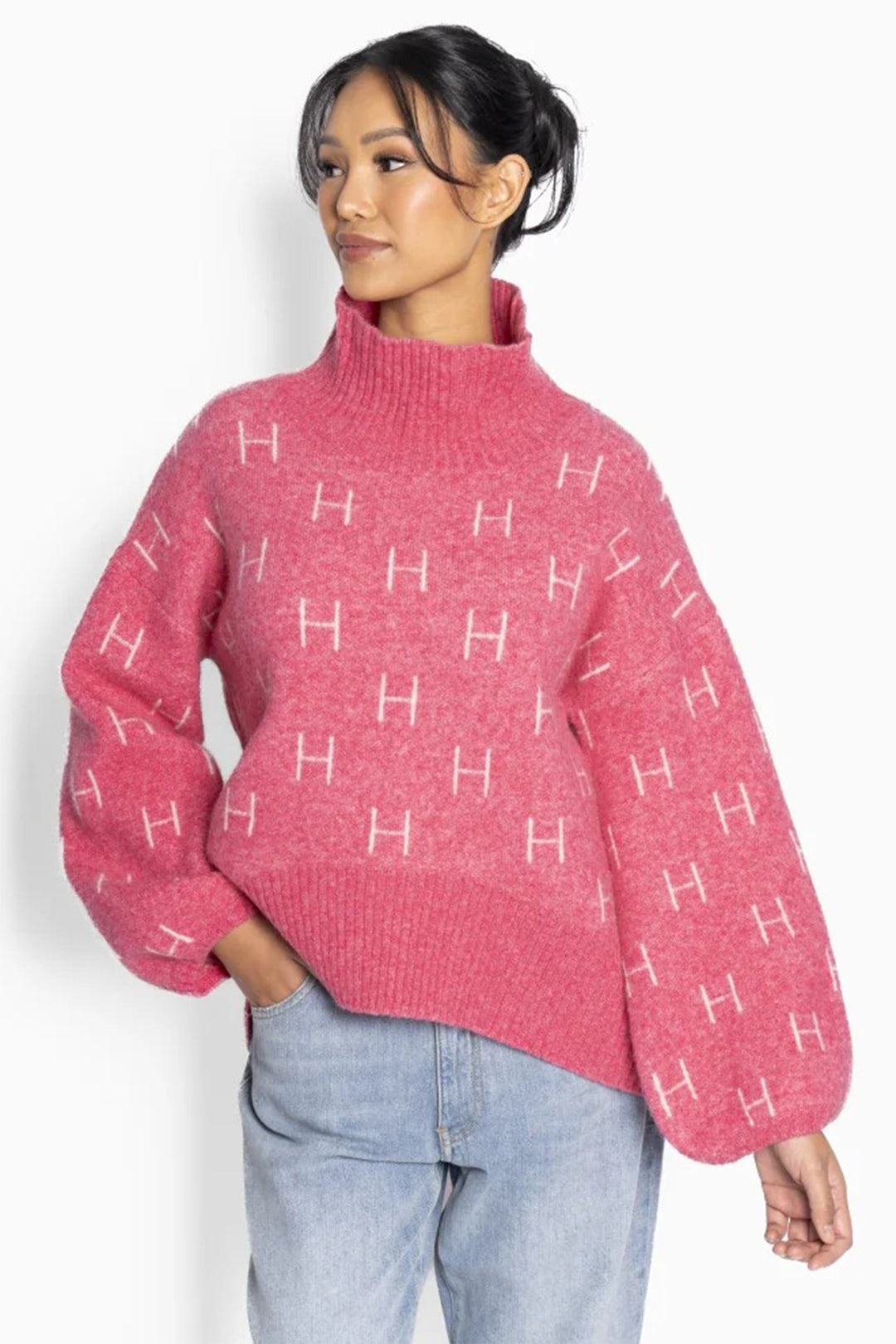 Person wearing a pink sweater with 'H' pattern on a white background