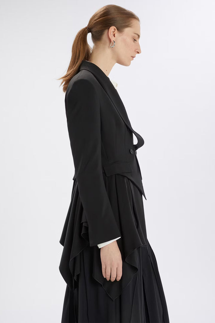 Woman wearing a black coat with ruffled details on a white background