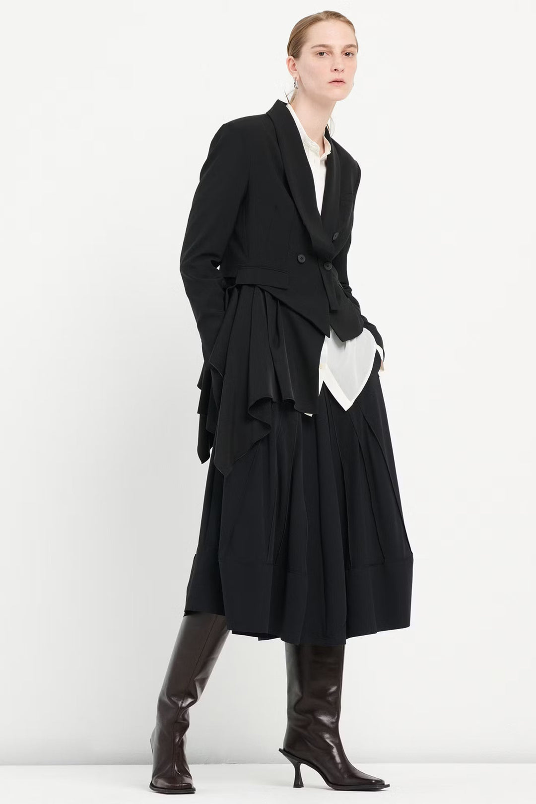 Person wearing a black coat and boots on a white background
