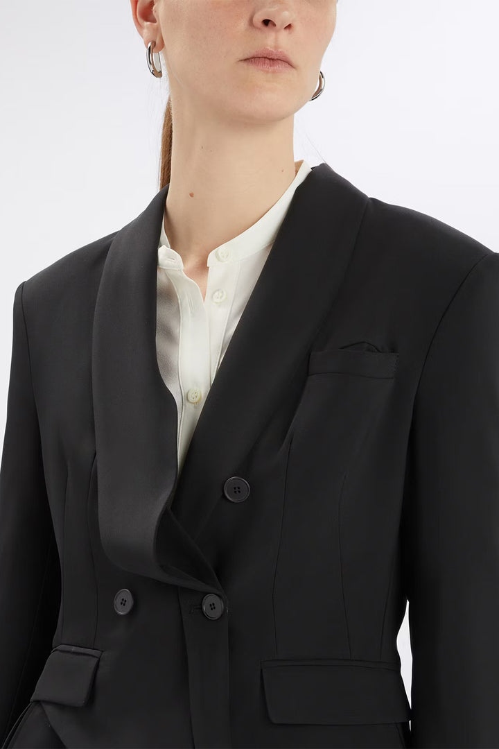 Person wearing a black blazer over a white shirt on a light gray background