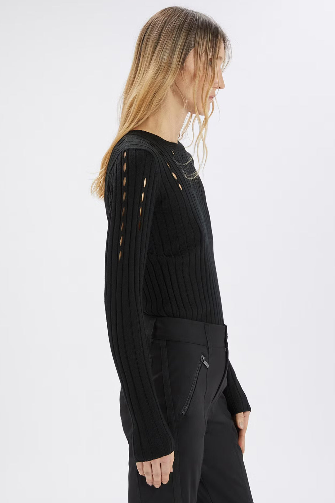 Person wearing a black ribbed sweater with cut-out details on a white background