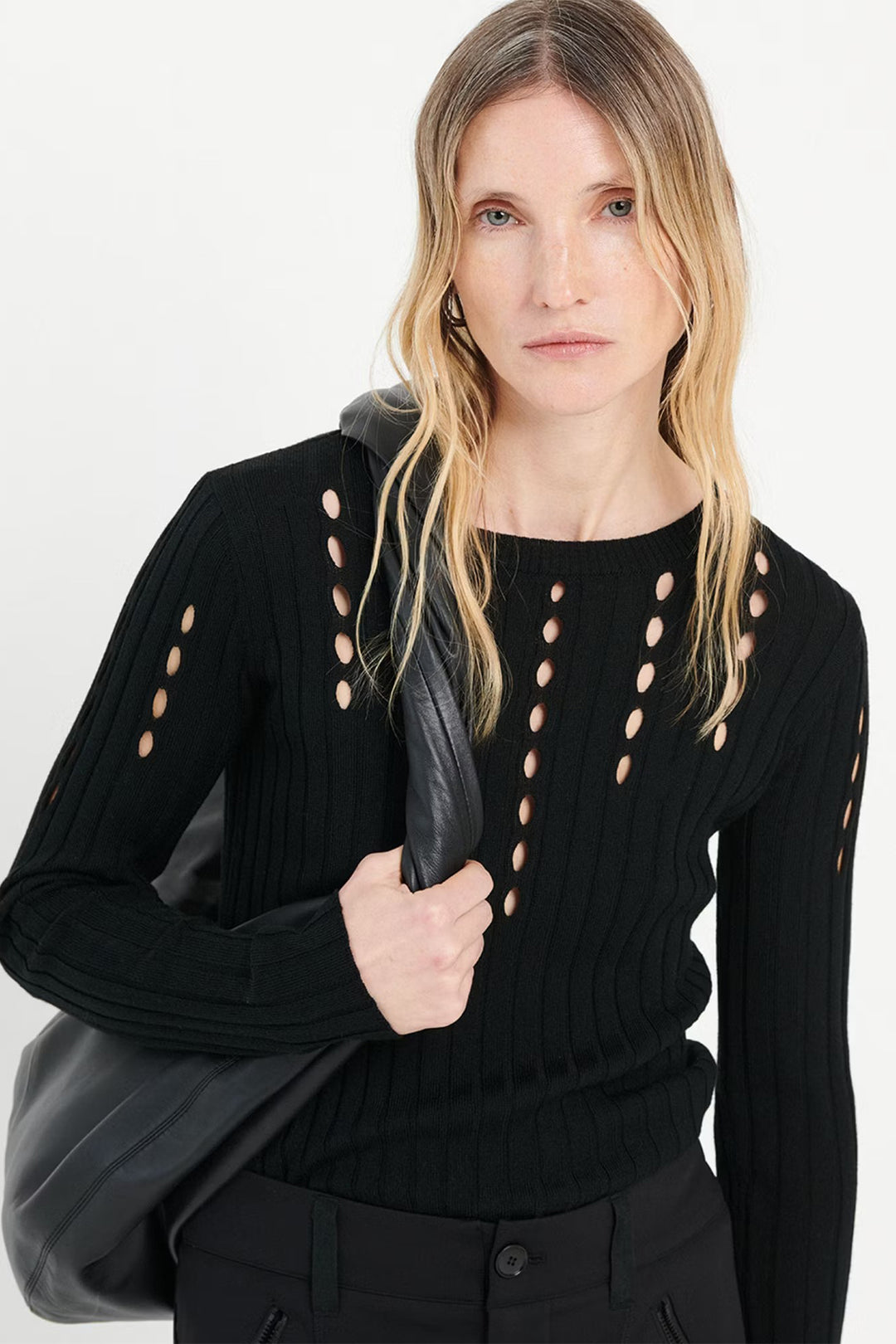 Woman wearing a black top with cut-out details on a white background