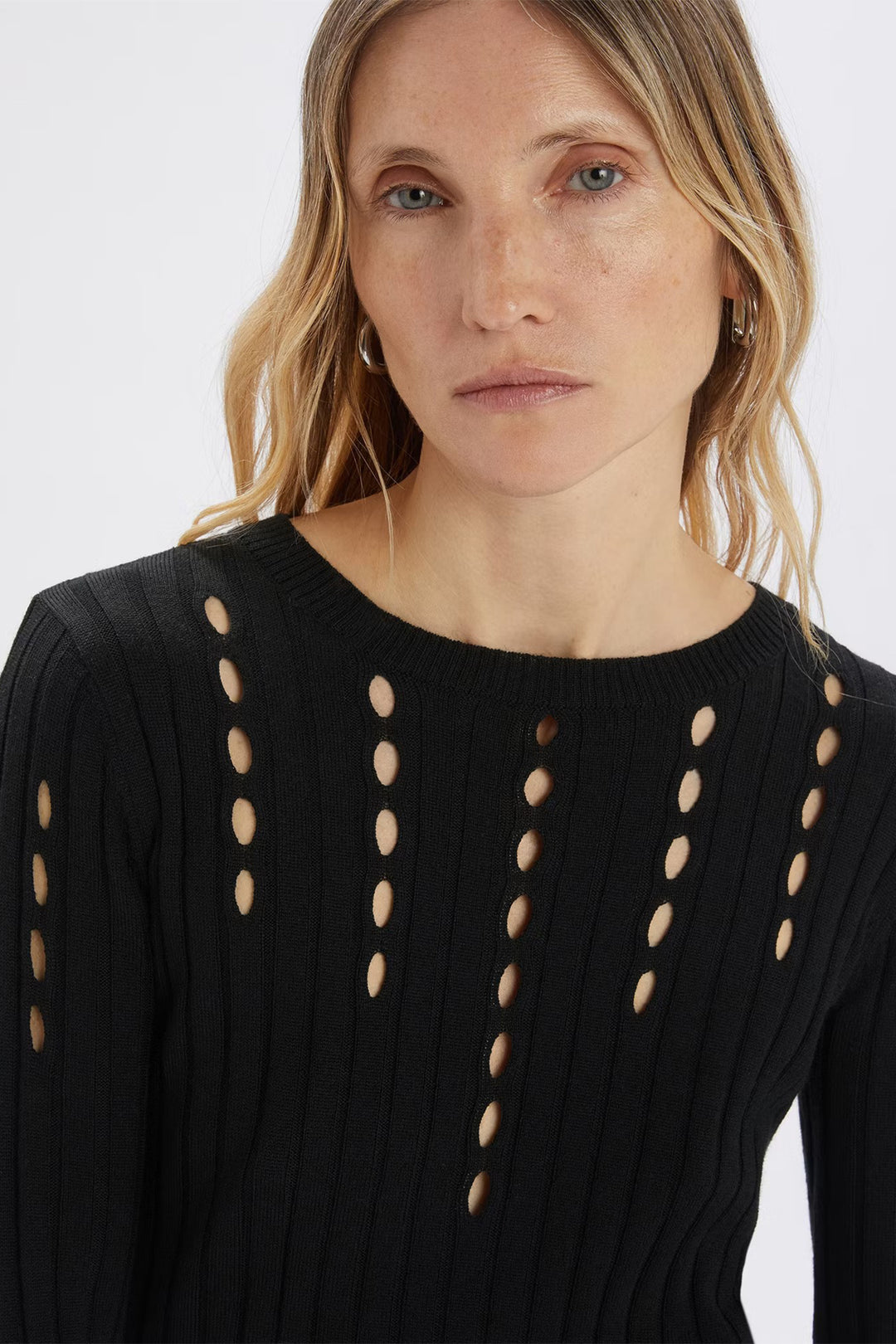Woman wearing a black sweater with cut-out designs on a white background