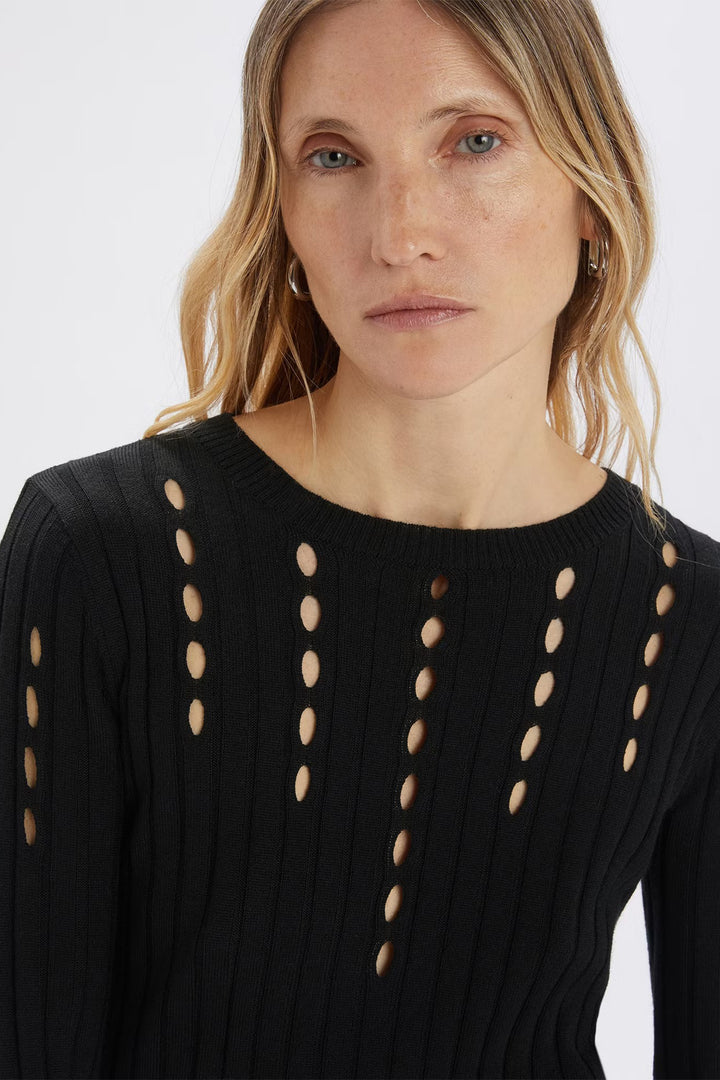 Woman wearing a black sweater with cut-out designs on a white background