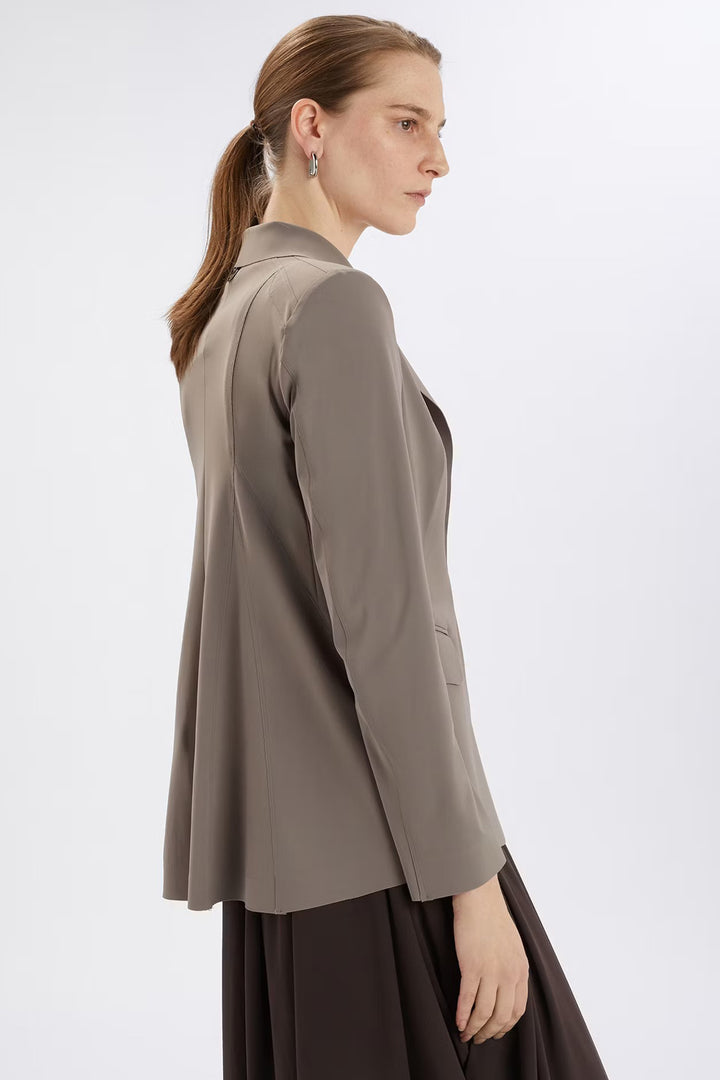 Woman wearing a beige blazer over a dark dress on a white background
