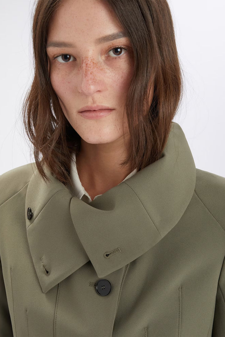 Person wearing a green coat with a white background