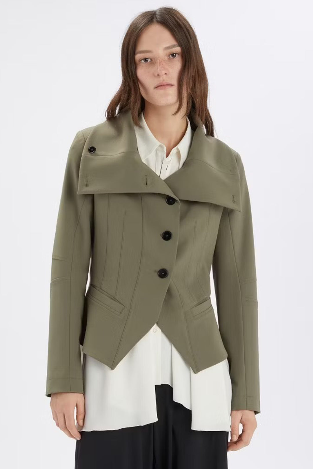 Woman wearing a green coat over a white shirt on a white background