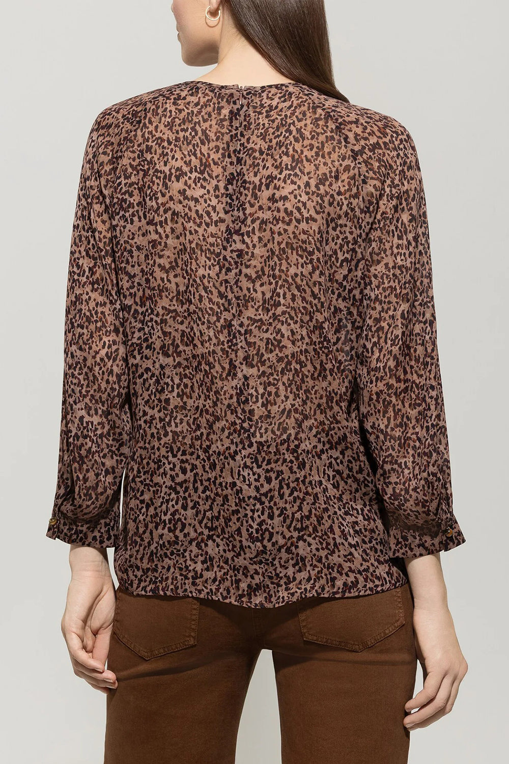 Person wearing a leopard print blouse and brown pants on a plain background