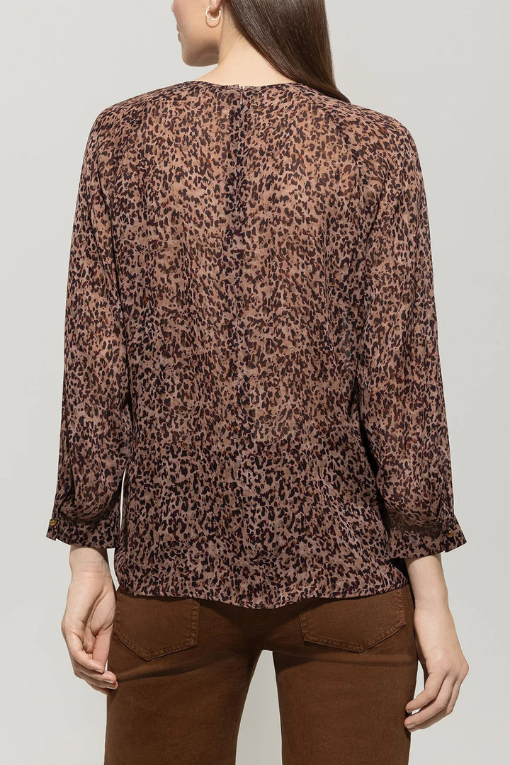 Person wearing a leopard print blouse and brown pants on a plain background