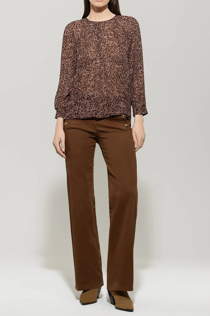Person wearing a brown patterned top and brown pants on a white background