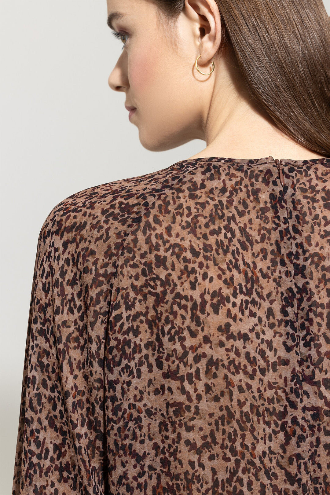 Woman wearing a leopard print top with a plain background