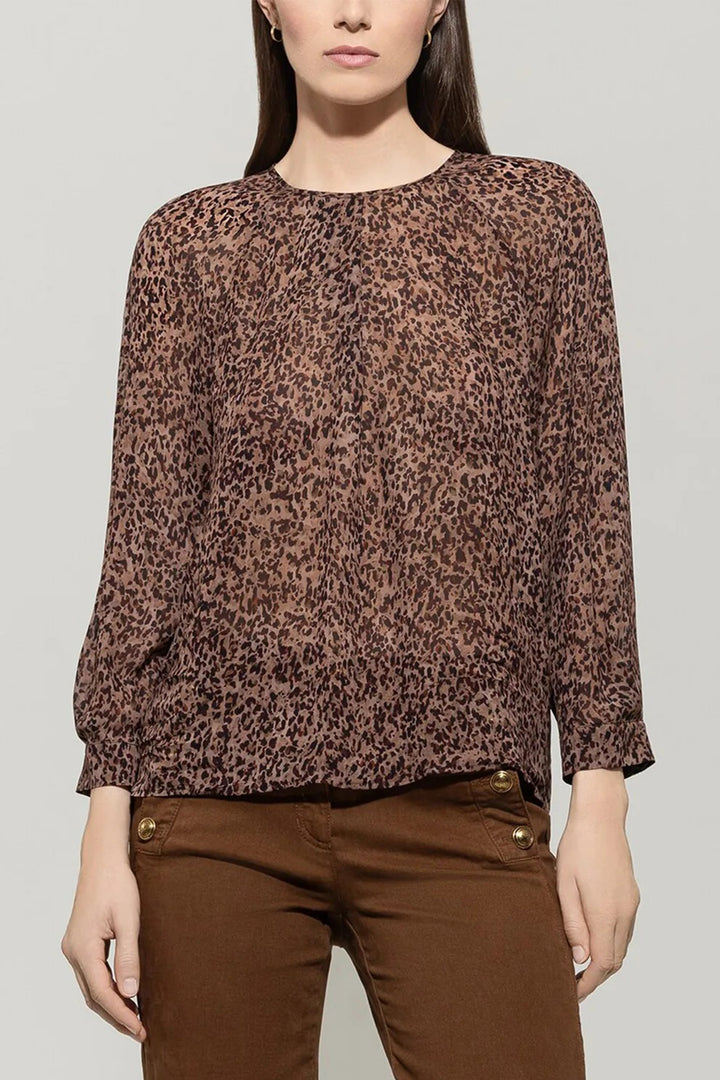 Woman wearing a brown leopard print top and brown pants on a gray background