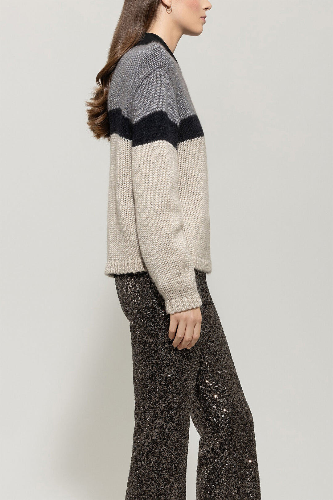 Person wearing a striped sweater and sequin pants on a plain background