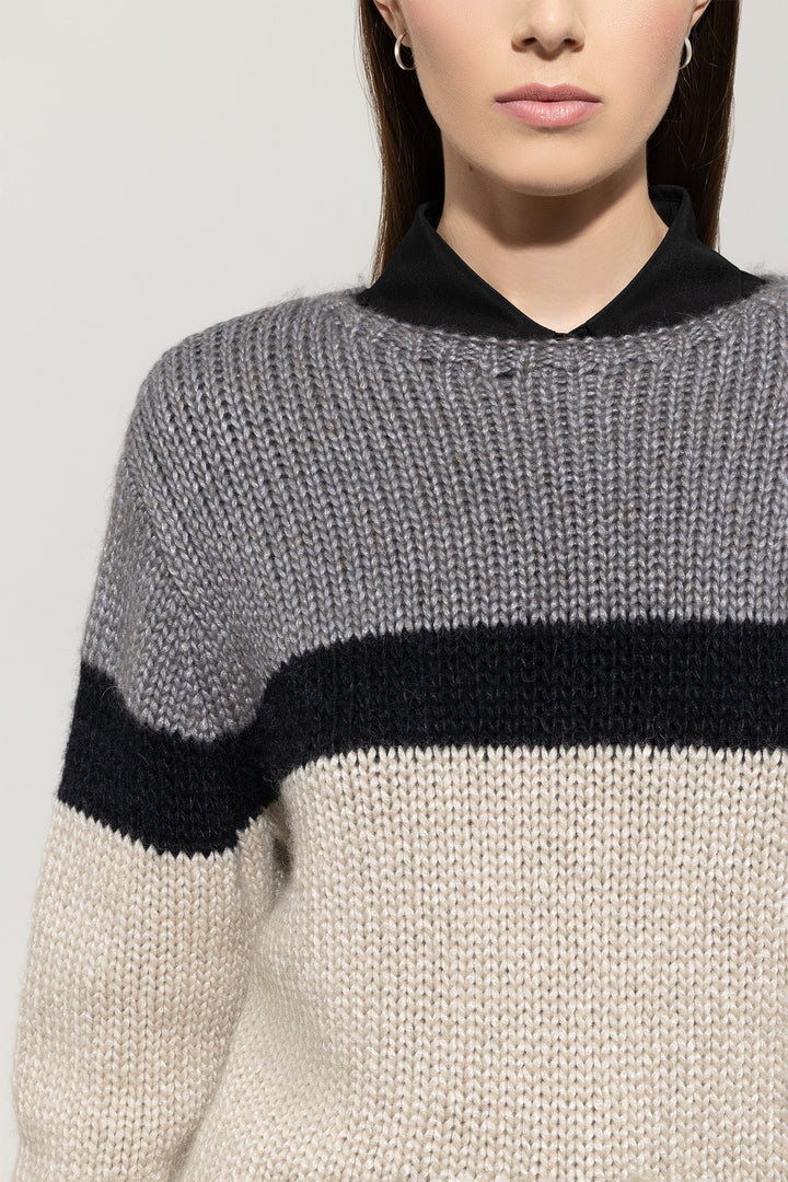 Close-up of a person wearing a gray and black sweater with a plain background