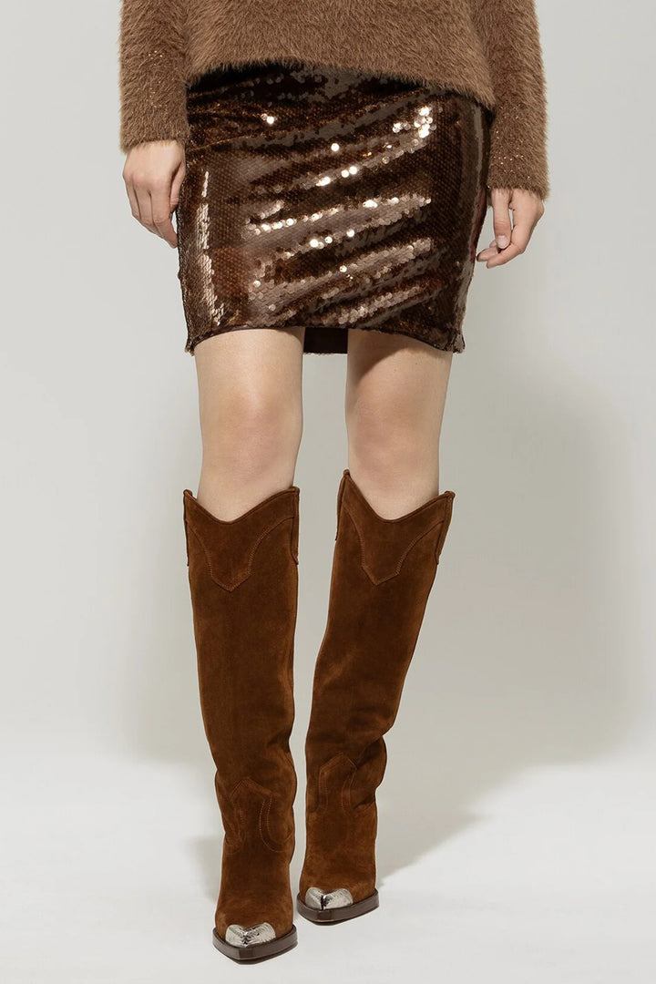 Person wearing a brown sequin skirt and knee-high brown boots on a white background