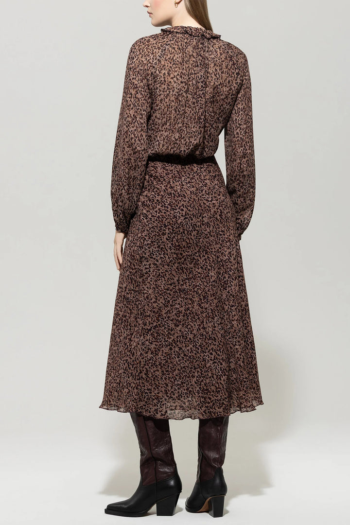 Woman wearing a patterned dress with long sleeves and a high collar on a white background