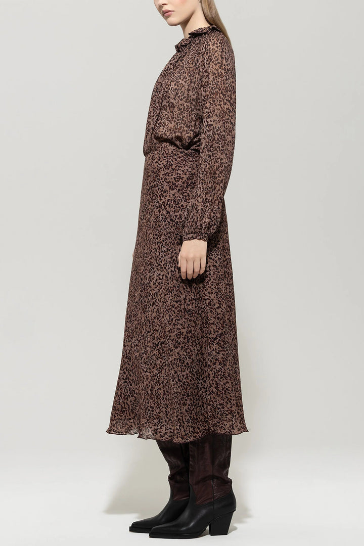 Woman wearing a long brown floral dress against a white background