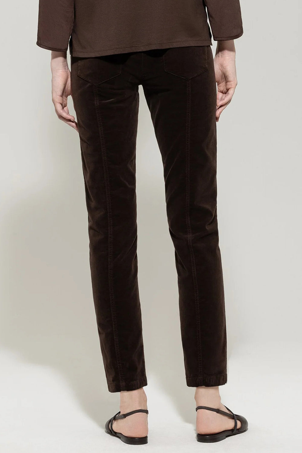Person wearing brown velvet pants on a white background