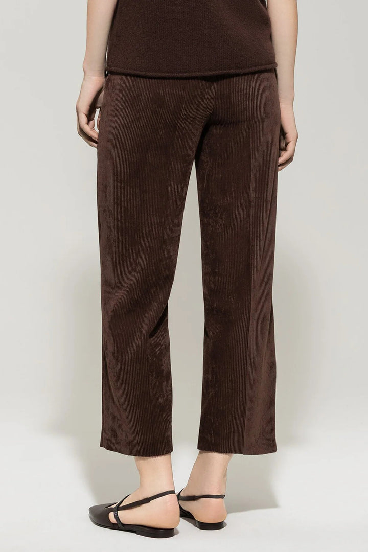 Brown corduroy pants worn by a person on a white background