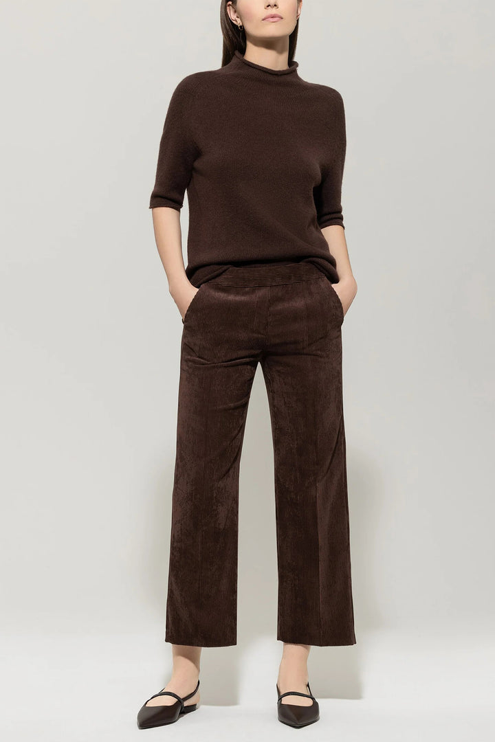 Person wearing a brown outfit with a sweater and pants on a white background