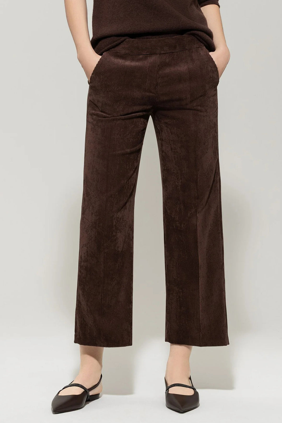 Brown corduroy pants worn by a person on a plain background