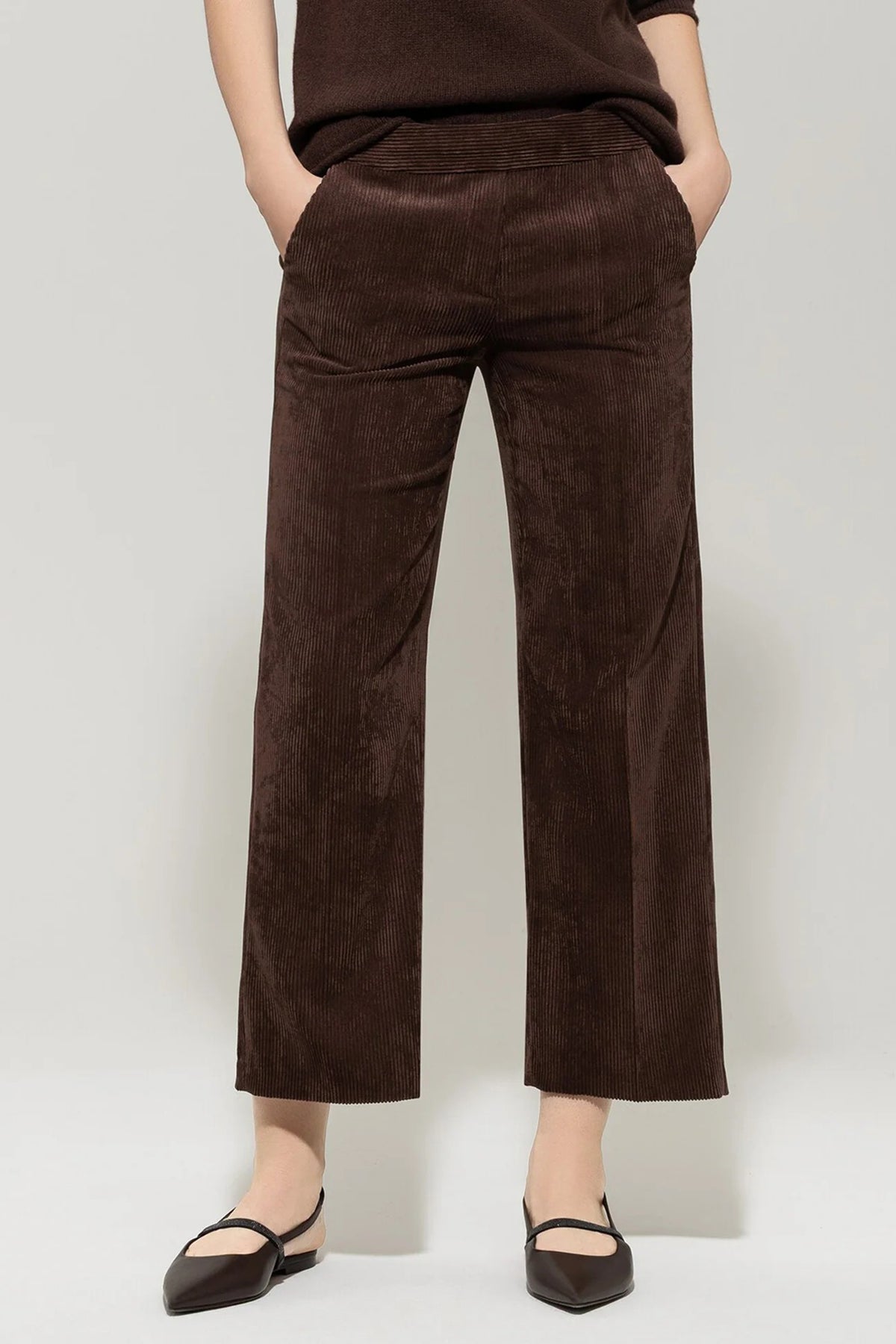 Brown corduroy pants worn by a person on a plain background