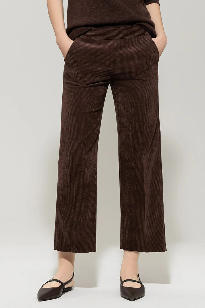 Brown corduroy pants worn by a person on a plain background