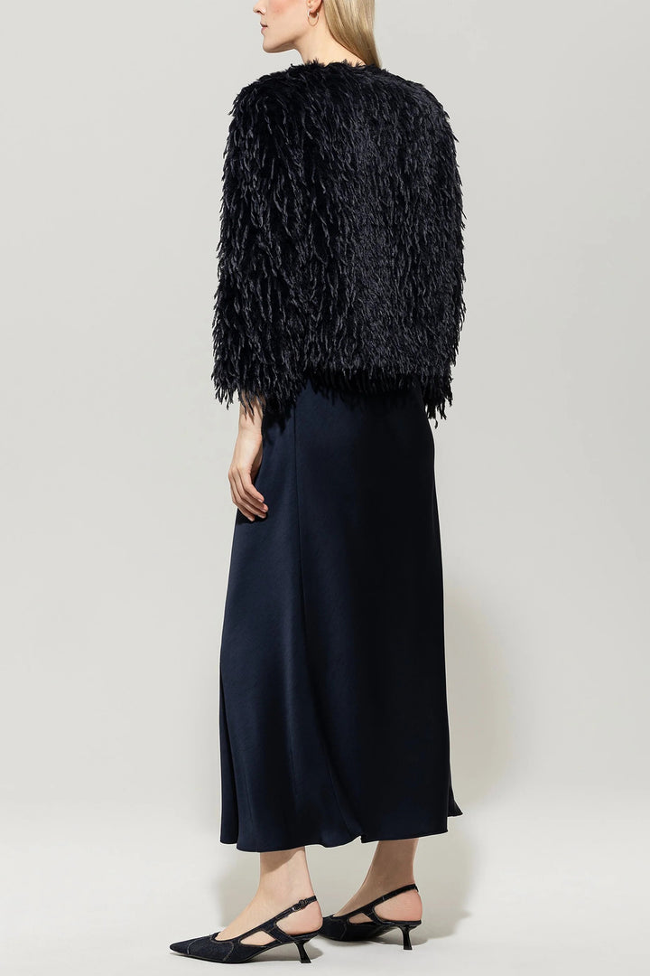 Person wearing a navy textured jacket over a navy dress on a white background