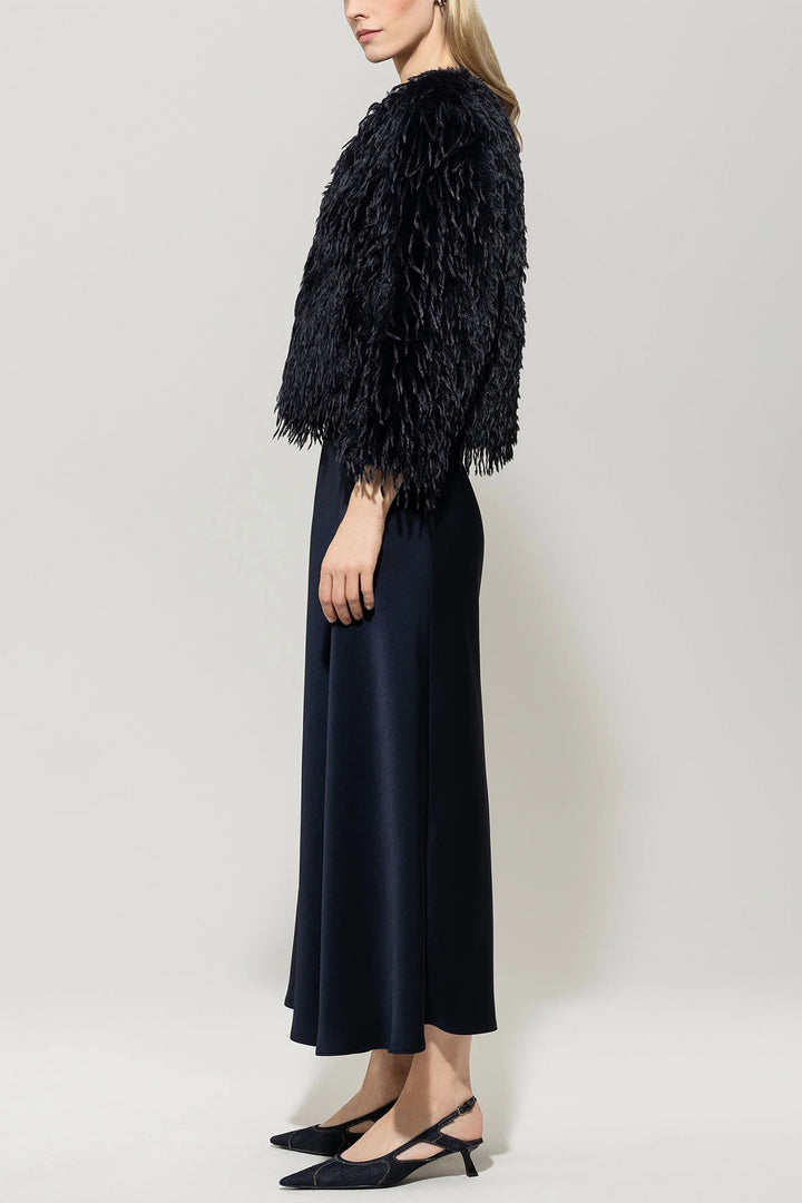 Woman wearing a navy feathered shrug over a dark dress against a white background