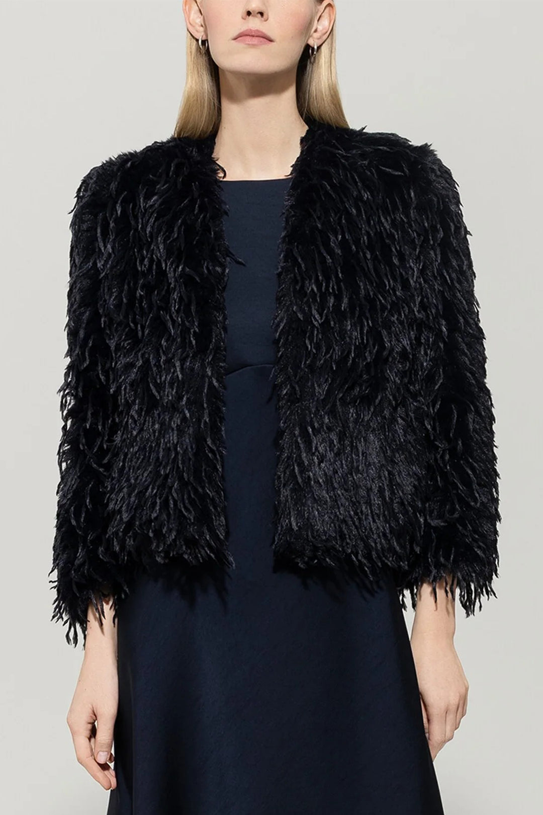 Woman wearing a navy shaggy jacket against a plain background