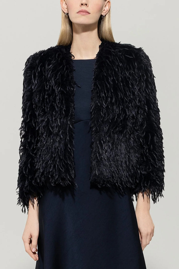 Woman wearing a navy shaggy jacket against a plain background