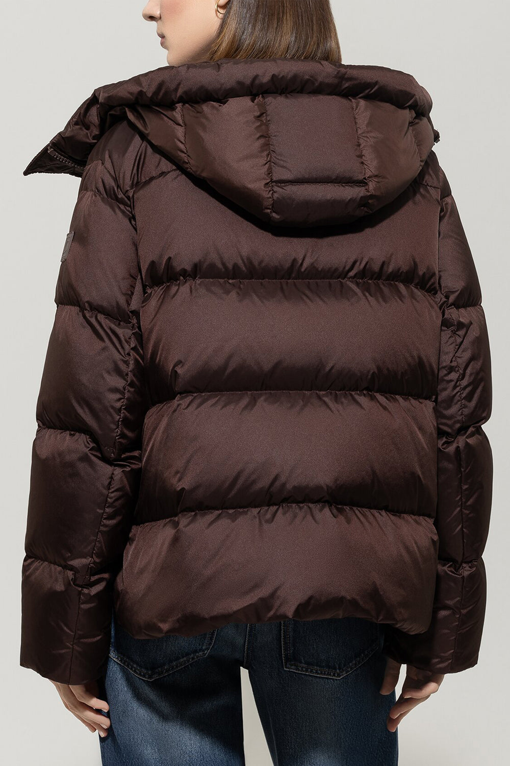 Brown puffer jacket worn by a person on a plain background
