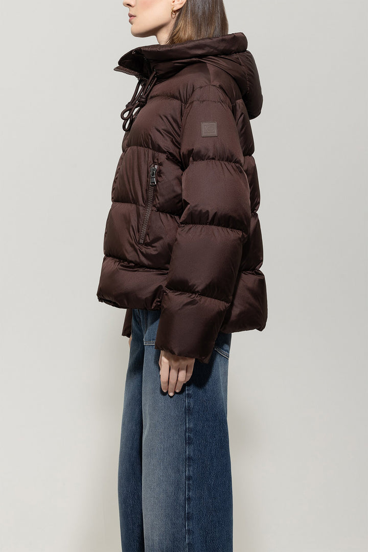 Person wearing a brown puffer jacket against a plain background