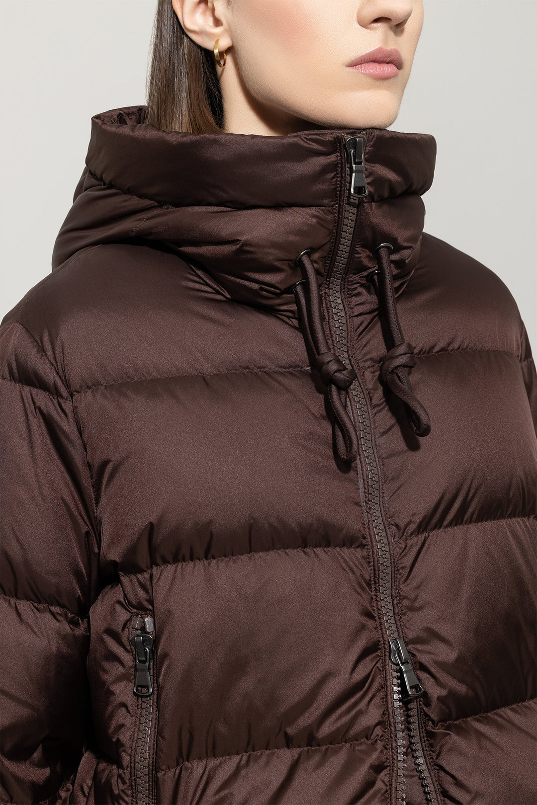 Brown puffer jacket worn by a person on a plain background
